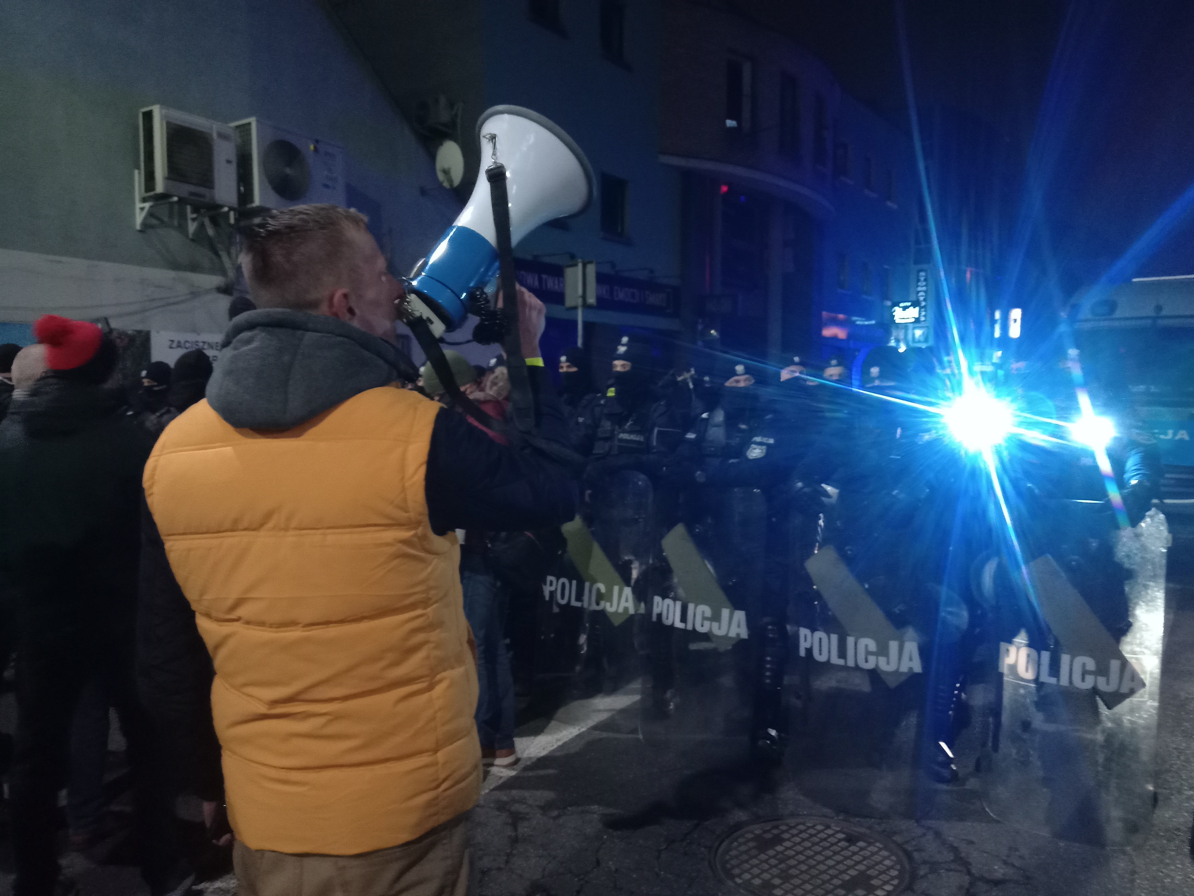 Krzysztof Kieś przez megafon apeluje o nieagresję, chwilę potem jest wciągnięty przez policję